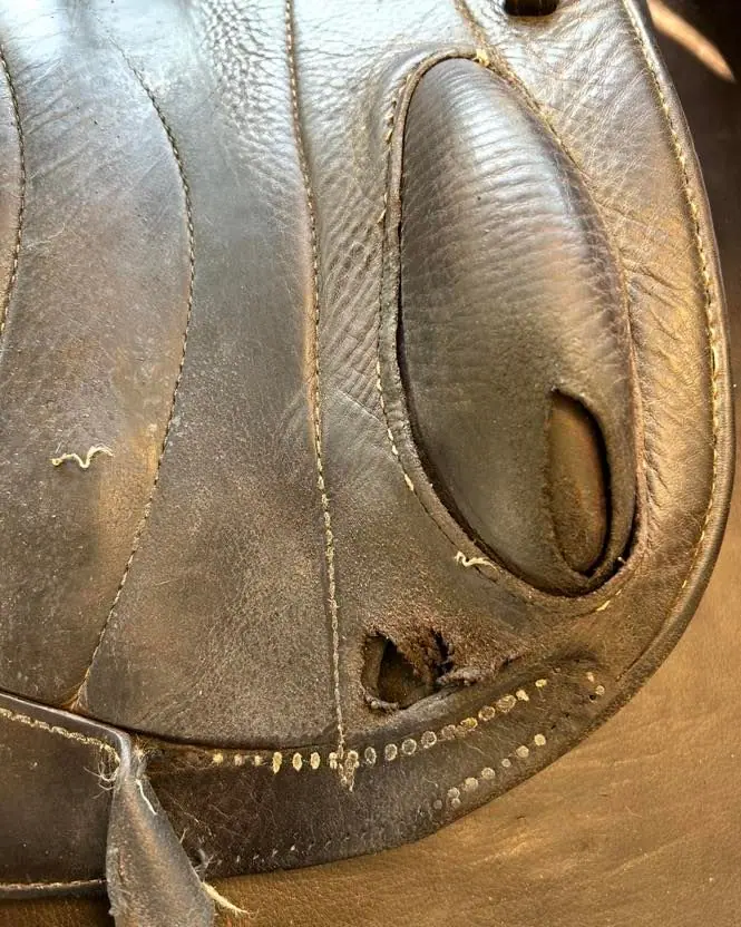 The same saddle before repair, worn and torn at the knee roll