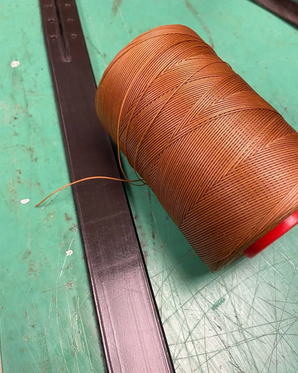 A spool of waxed linen thread on a leather strap